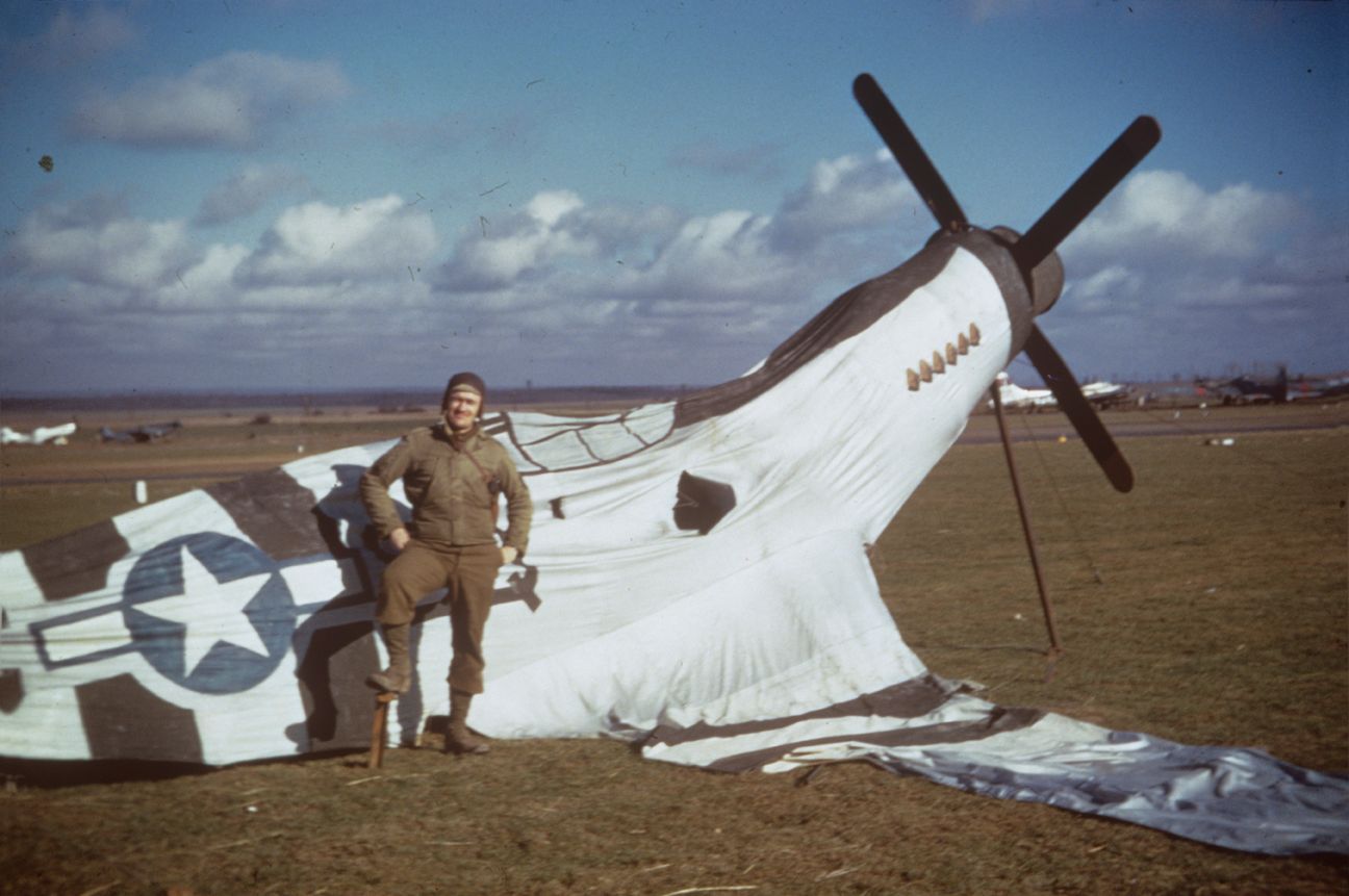 An airman of the 10th Photographic Reconnaissance Group with an inflatable decoy P-51 Mustang..jpg